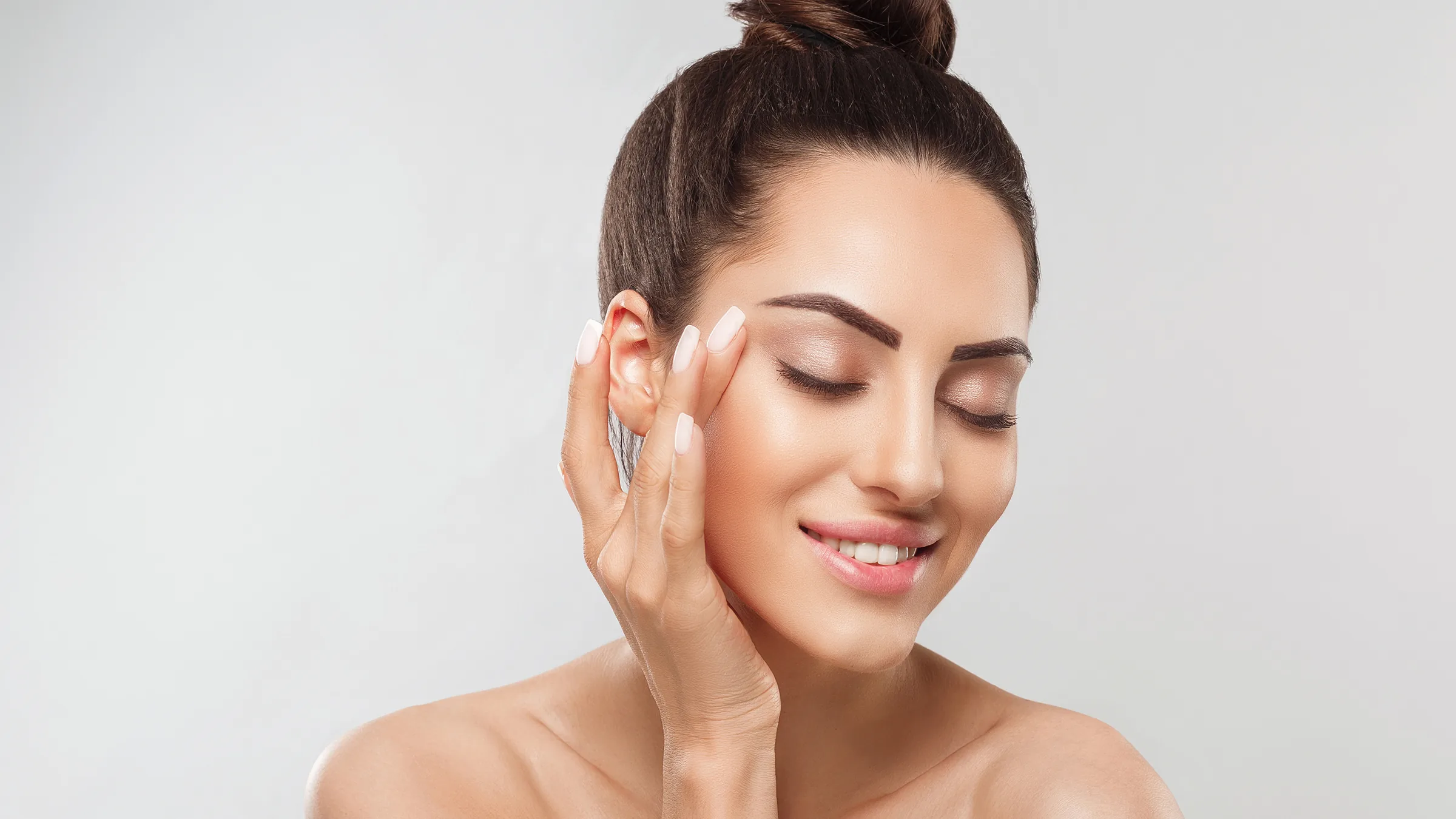 beautiful woman touching face with glowing, radiant skin